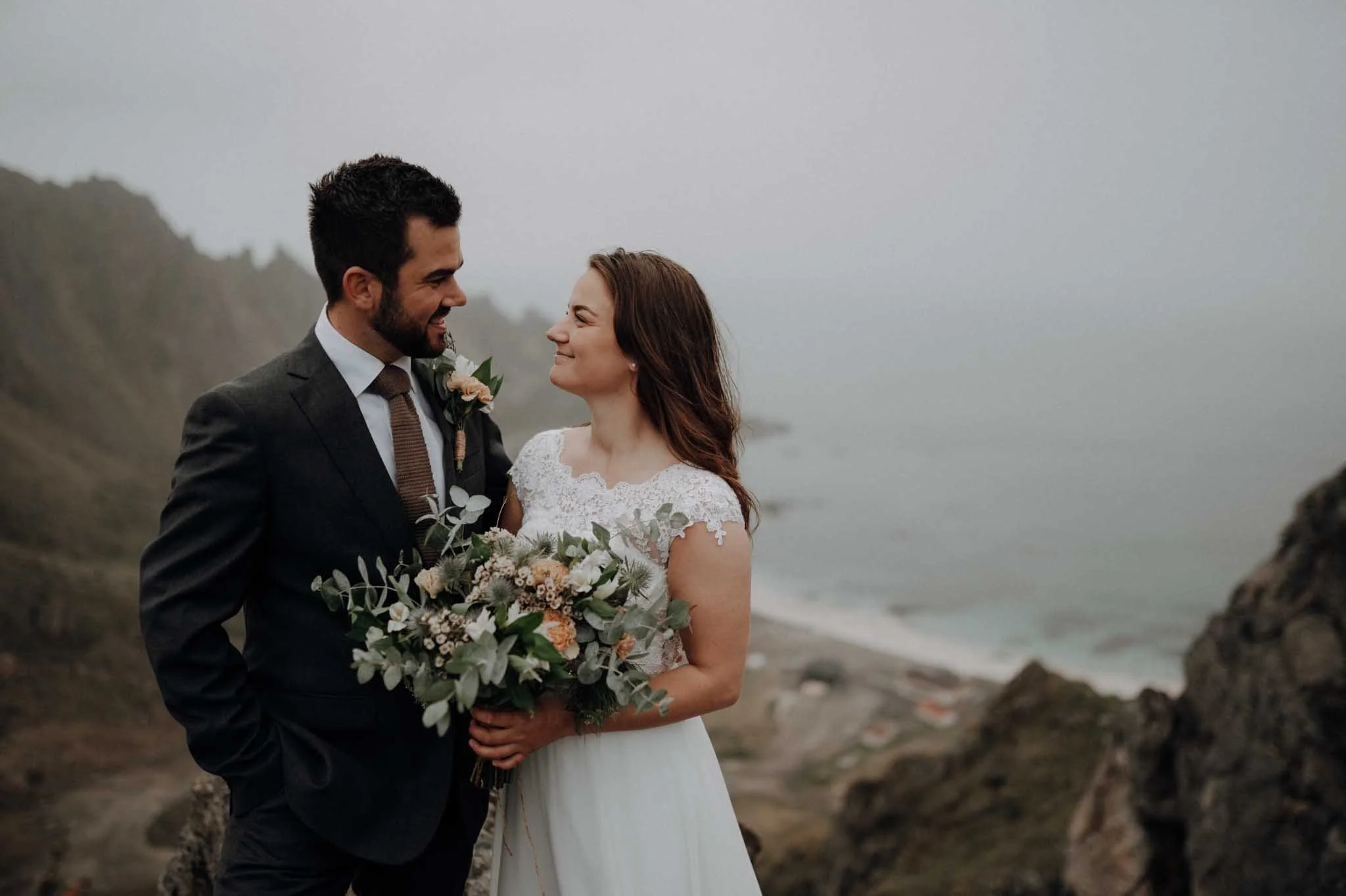 Portrettfotografering av et brudepar. De smiler og ser på hverandre. Elopement. 