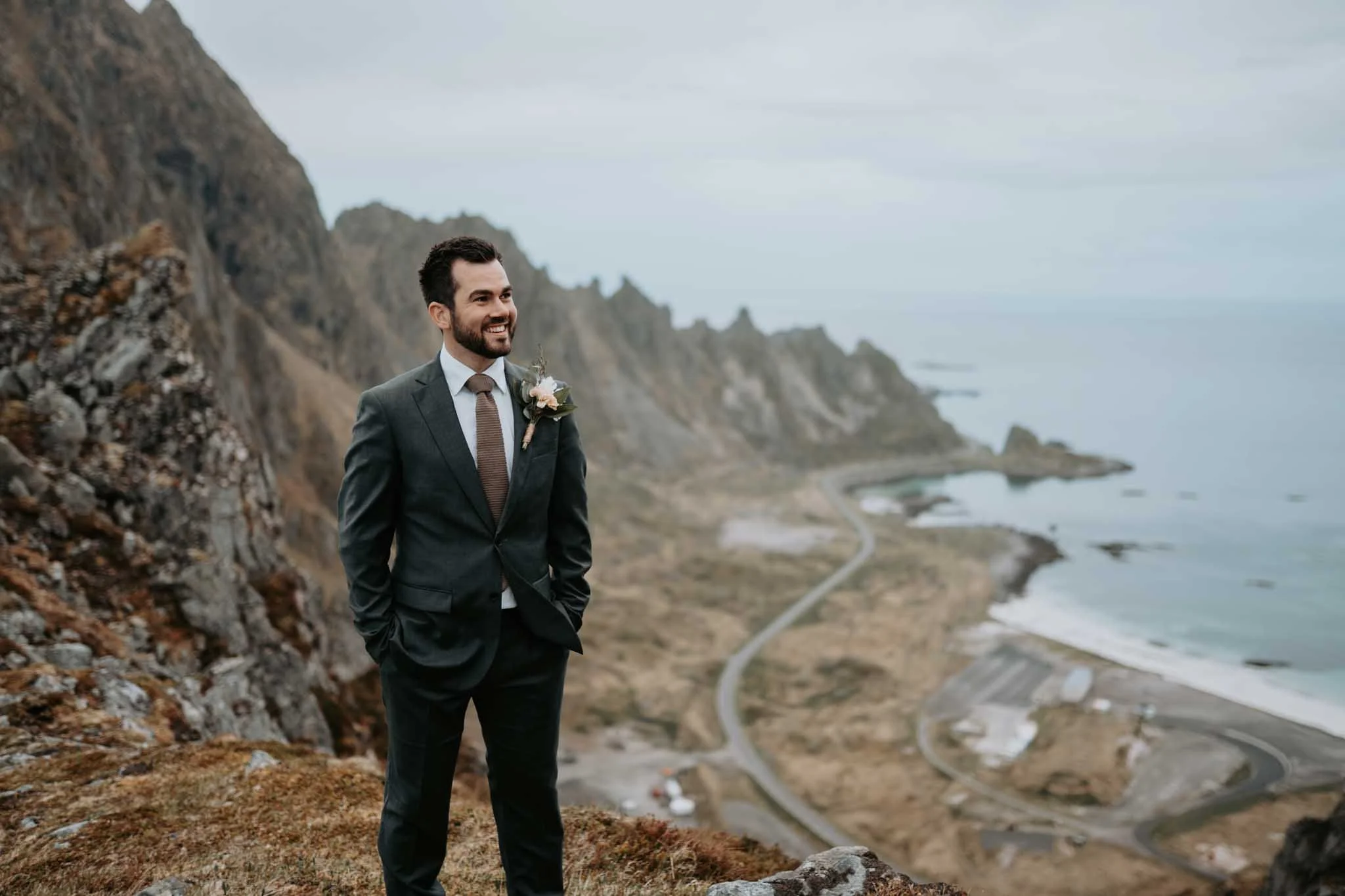 Portrett av brudgom som ser smilende på bruden med strand og fjell i bakgrunnen.