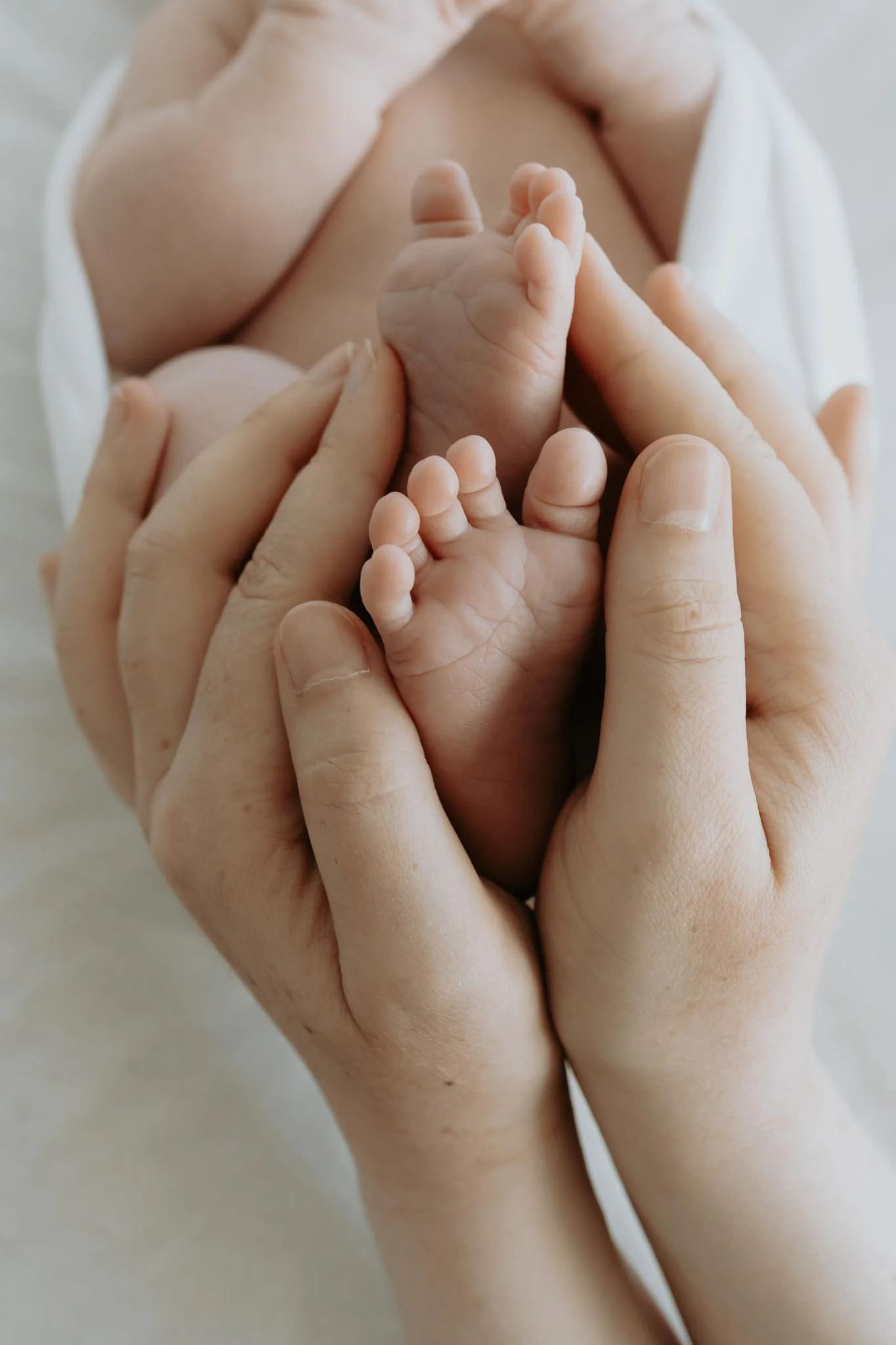 Mor holder rundt de søte føttene til den nyfødt babyen. 
