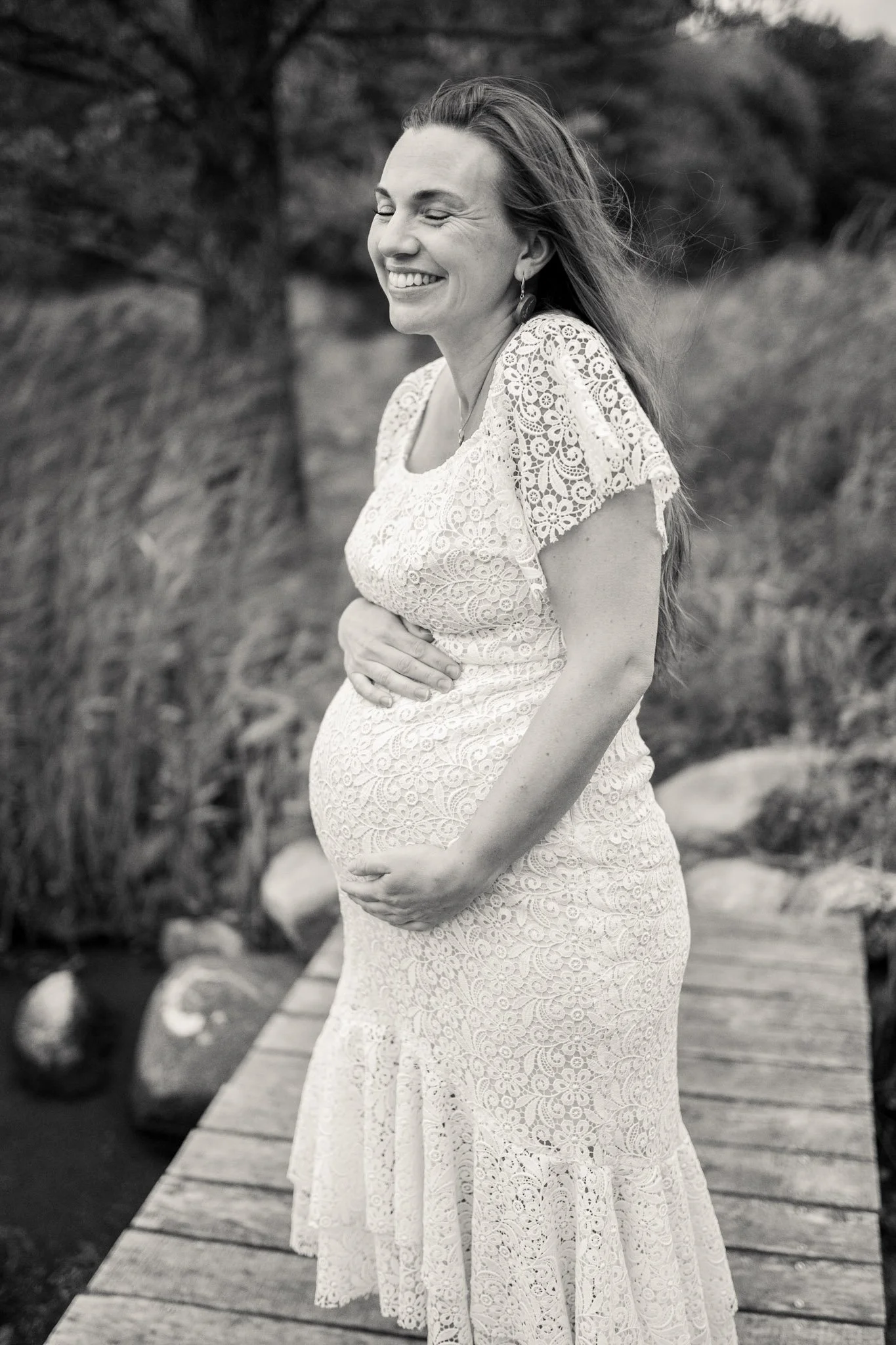 Gravidbilde av lykkelig dame. Smilende og avslappet. Holder på magen.