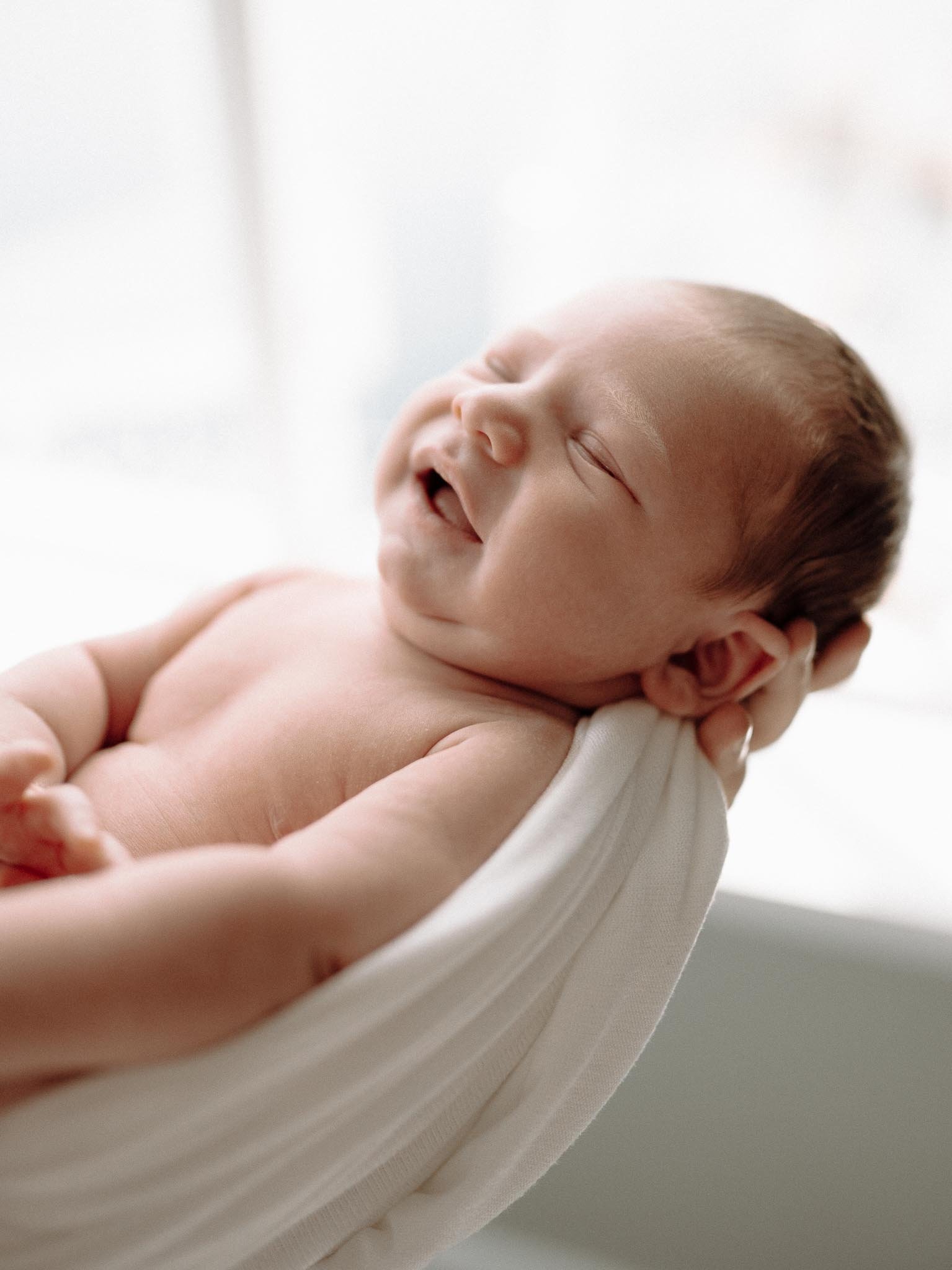 Mor holder nyfødt baby og babyen smiler. 
