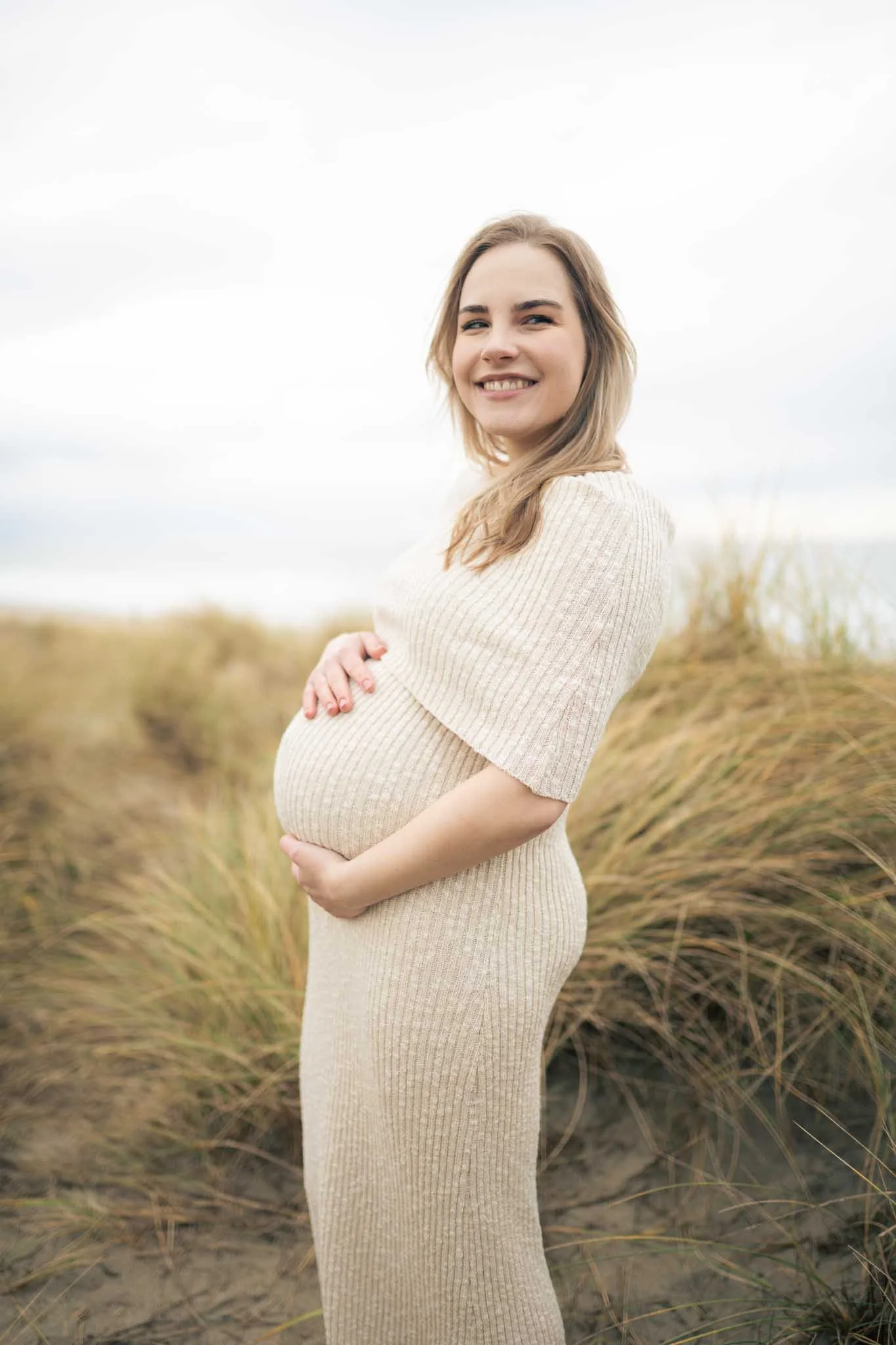 Gravidfotografering på stranda. Smilende og lykkelig.