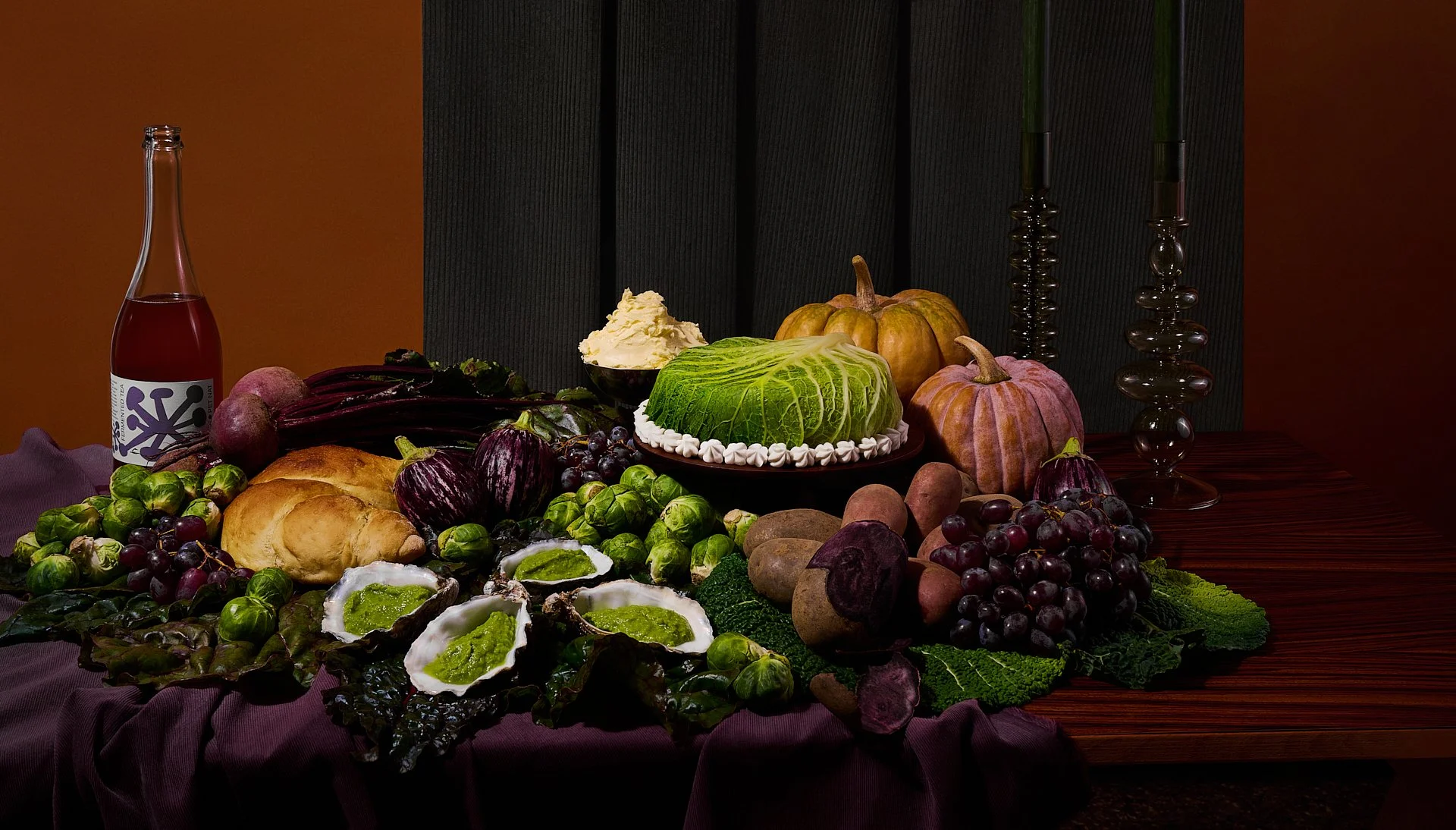A table set for a feast with vegetables, fruits, bread, and a bottle of wine, with dark candles and a dark background.