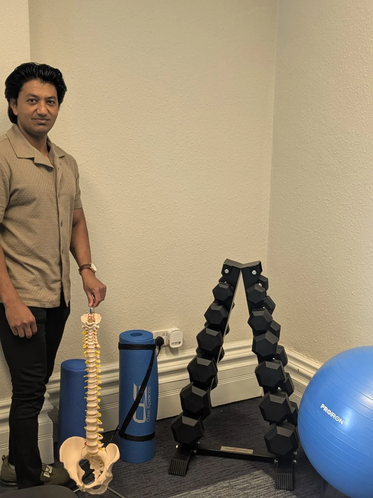 Physio clinic in Cardiff Oh One - photo of senior physio Raj near a spine model and equipment for exercise