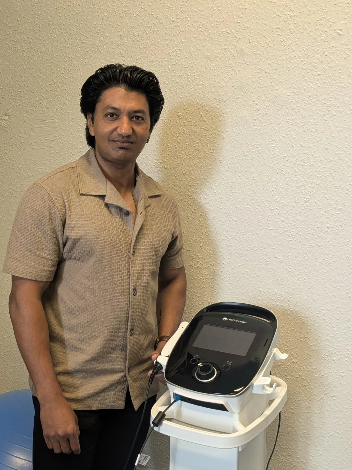 Man standing next to a medical device in a room with beige textured walls.