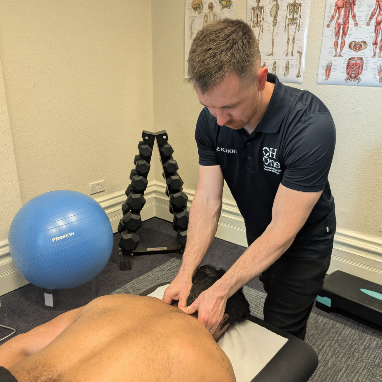 Rick (Physio) applying neck treatment to a patient who is lying face down on the physio bed