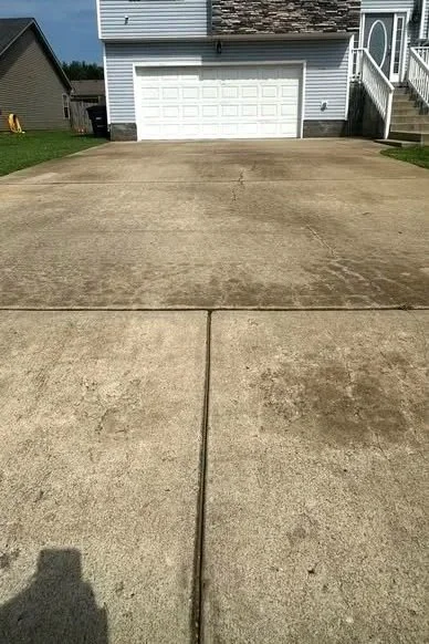 Concrete driveway in front of a white garage with a small staircase leading to the main door.