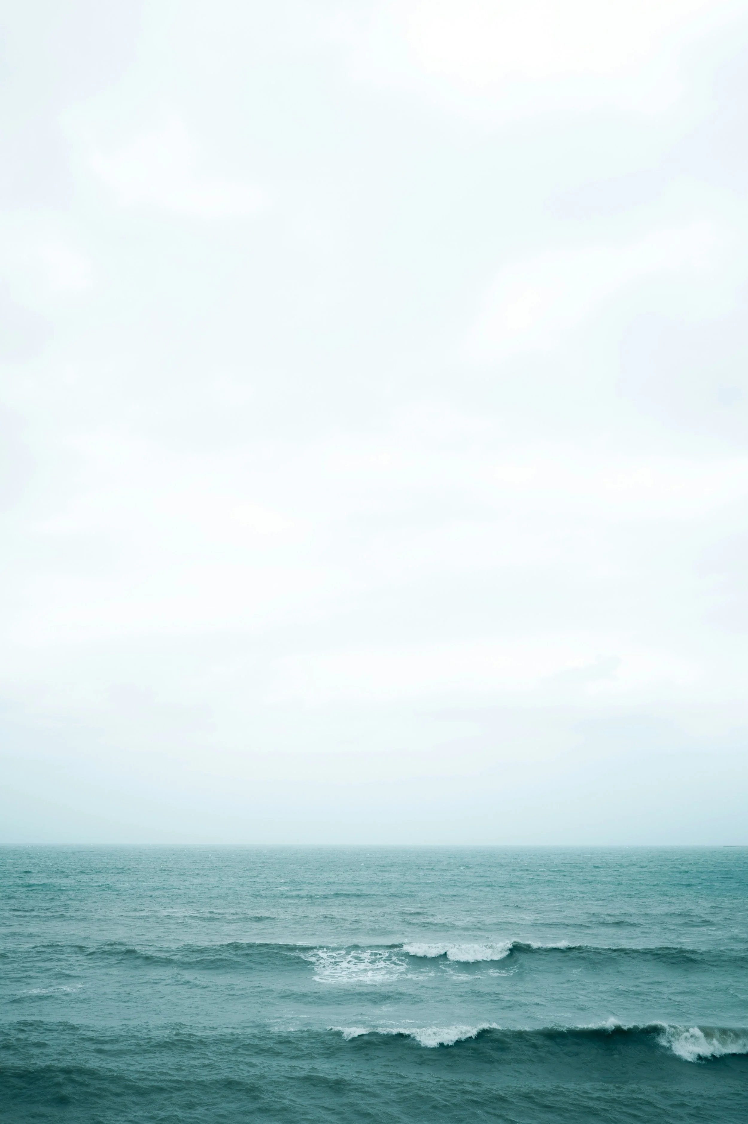 Overcast sky above a calm ocean with gentle waves.
