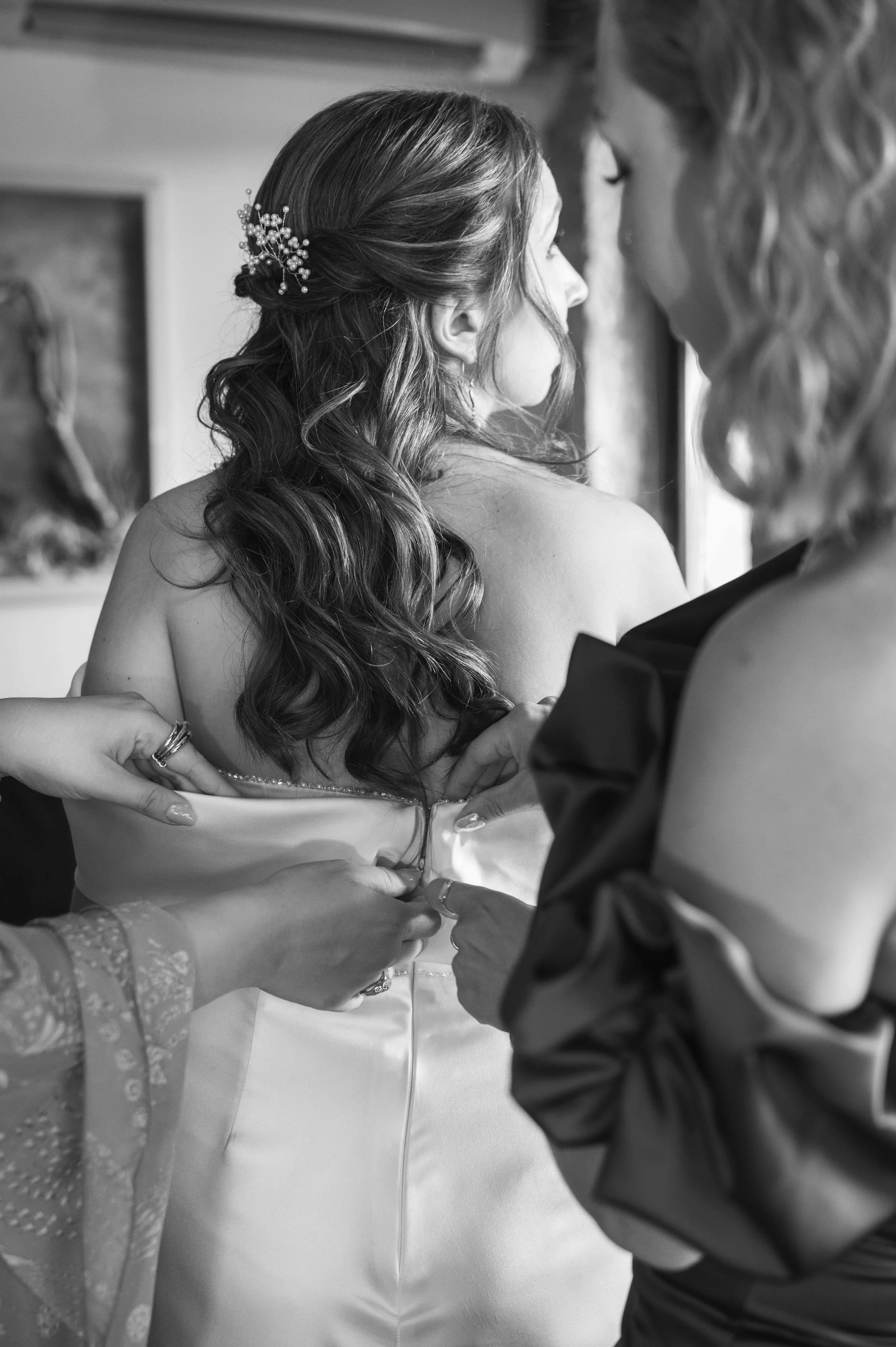 A bride getting help with her wedding dress from two women.