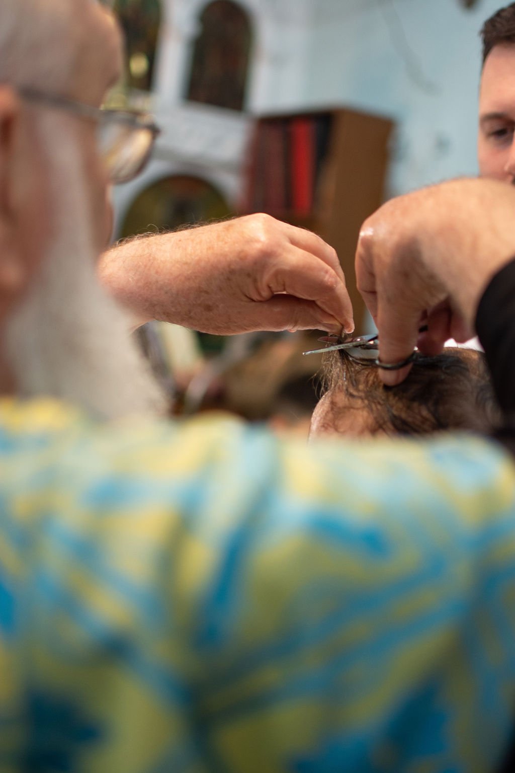 Barber giving a haircut to a customer with vintage decor in the background.