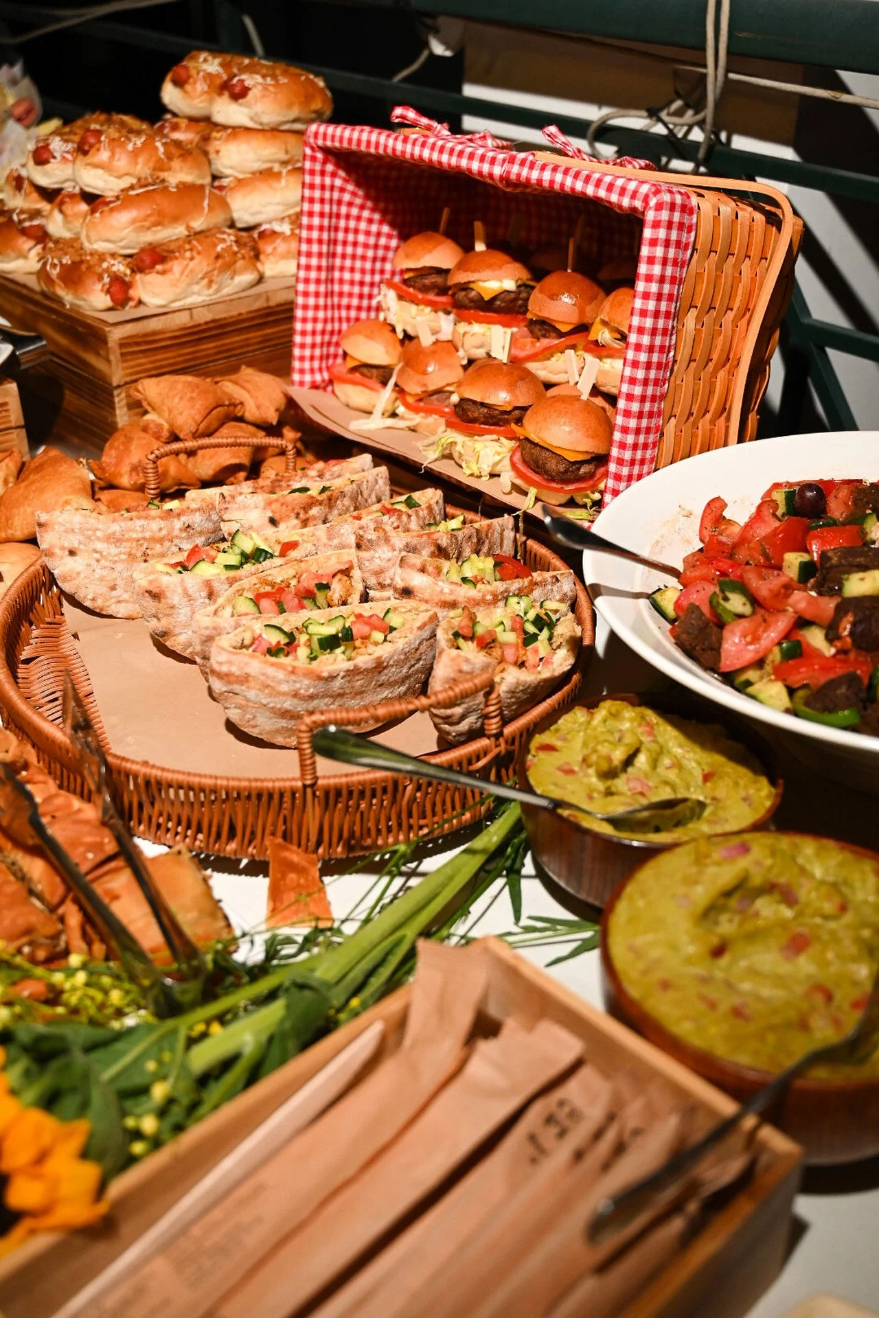 A variety of finger foods including sliders, wraps, salads, and dips displayed on a table at a buffet.