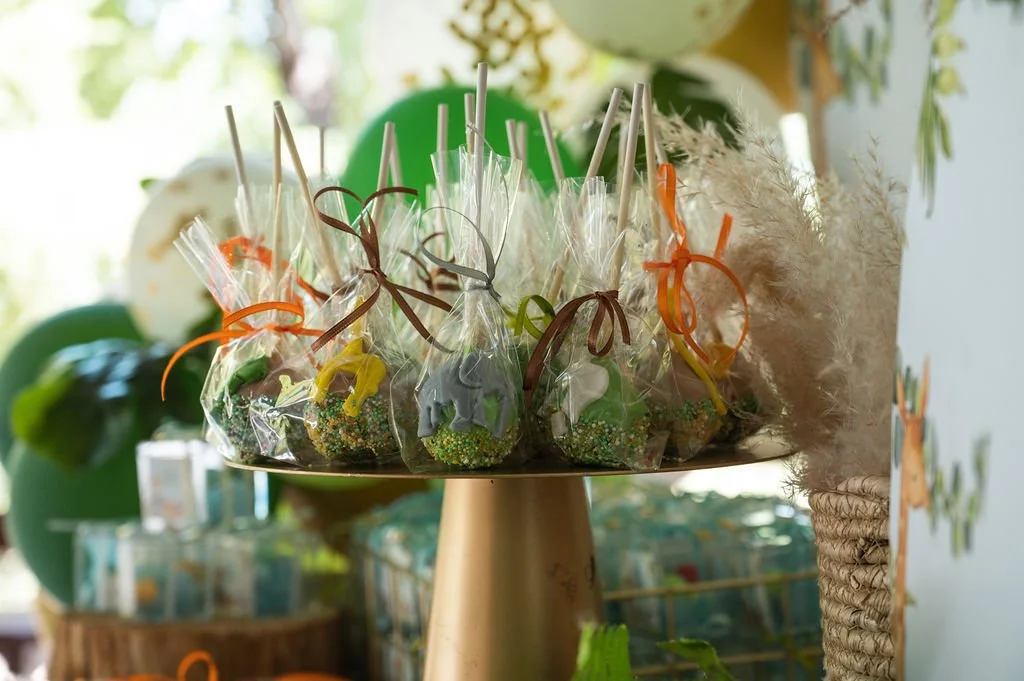 Easter-themed candies wrapped in clear bags with ribbons on a gold display stand, with a plush bunny and Easter decorations in the background.
