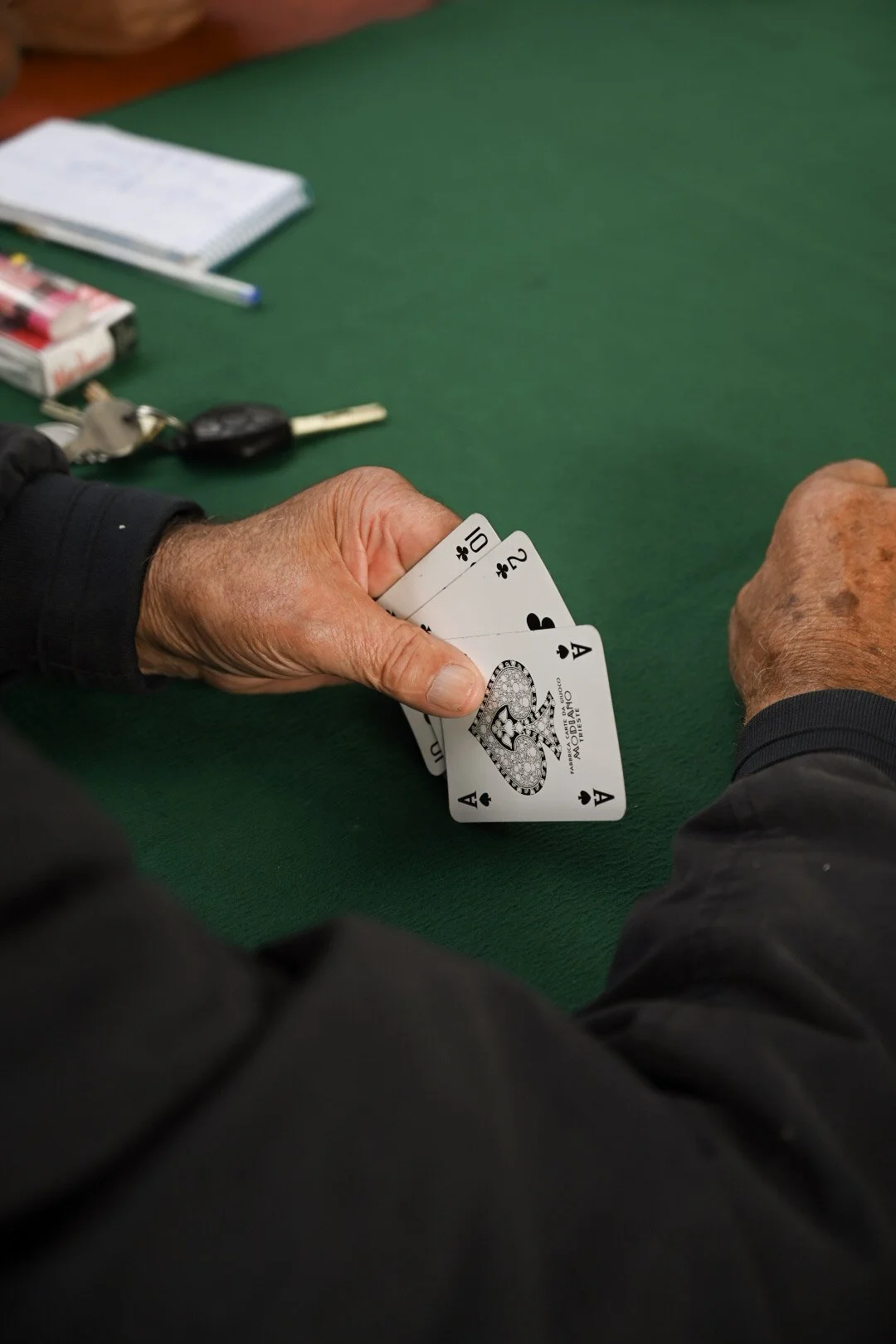 Person holding four aces playing cards at a green felt table in a card game.