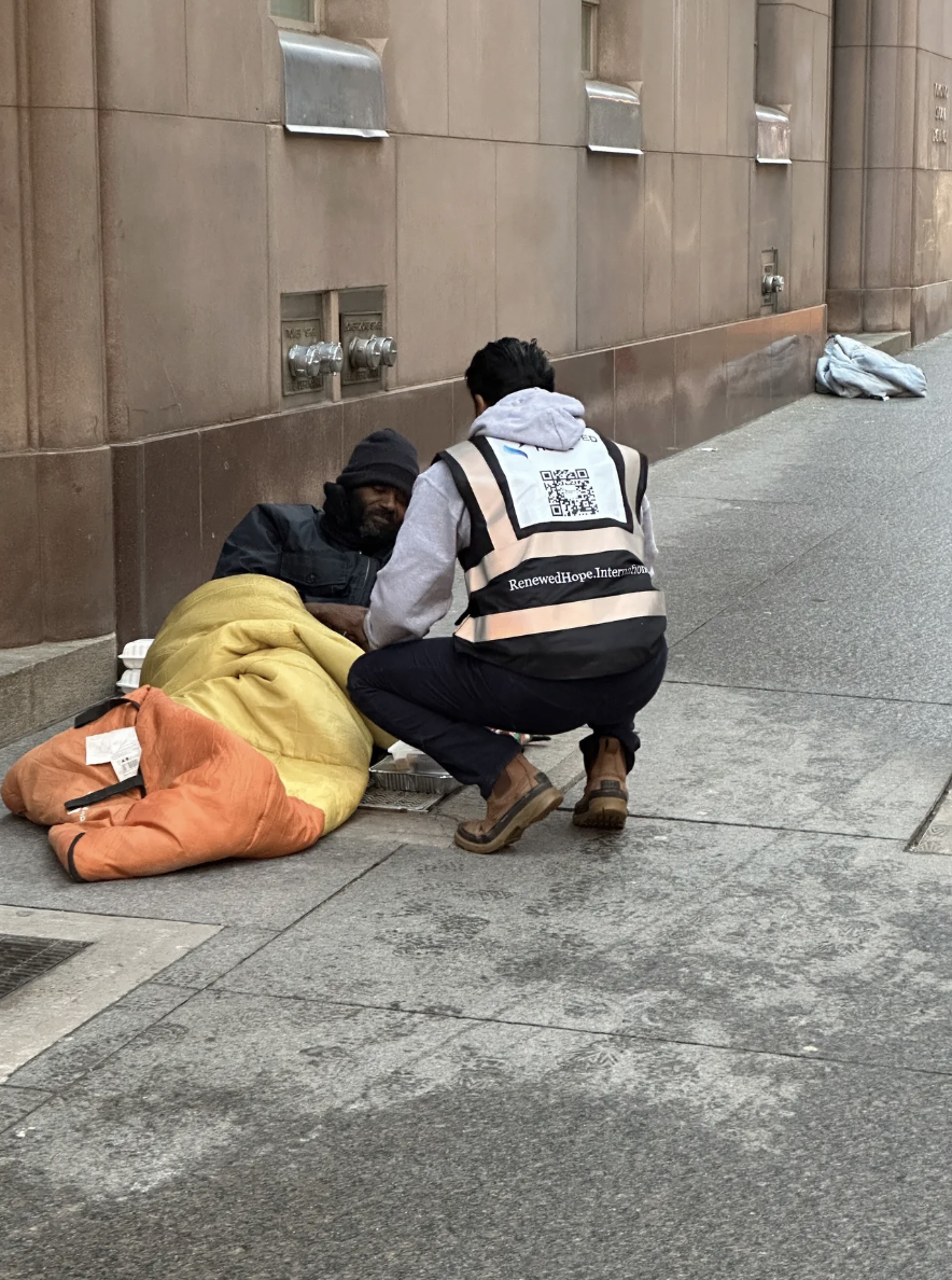 volunteer-kneeling-providing-help-to-homesless-man-lying-on-sidewalk