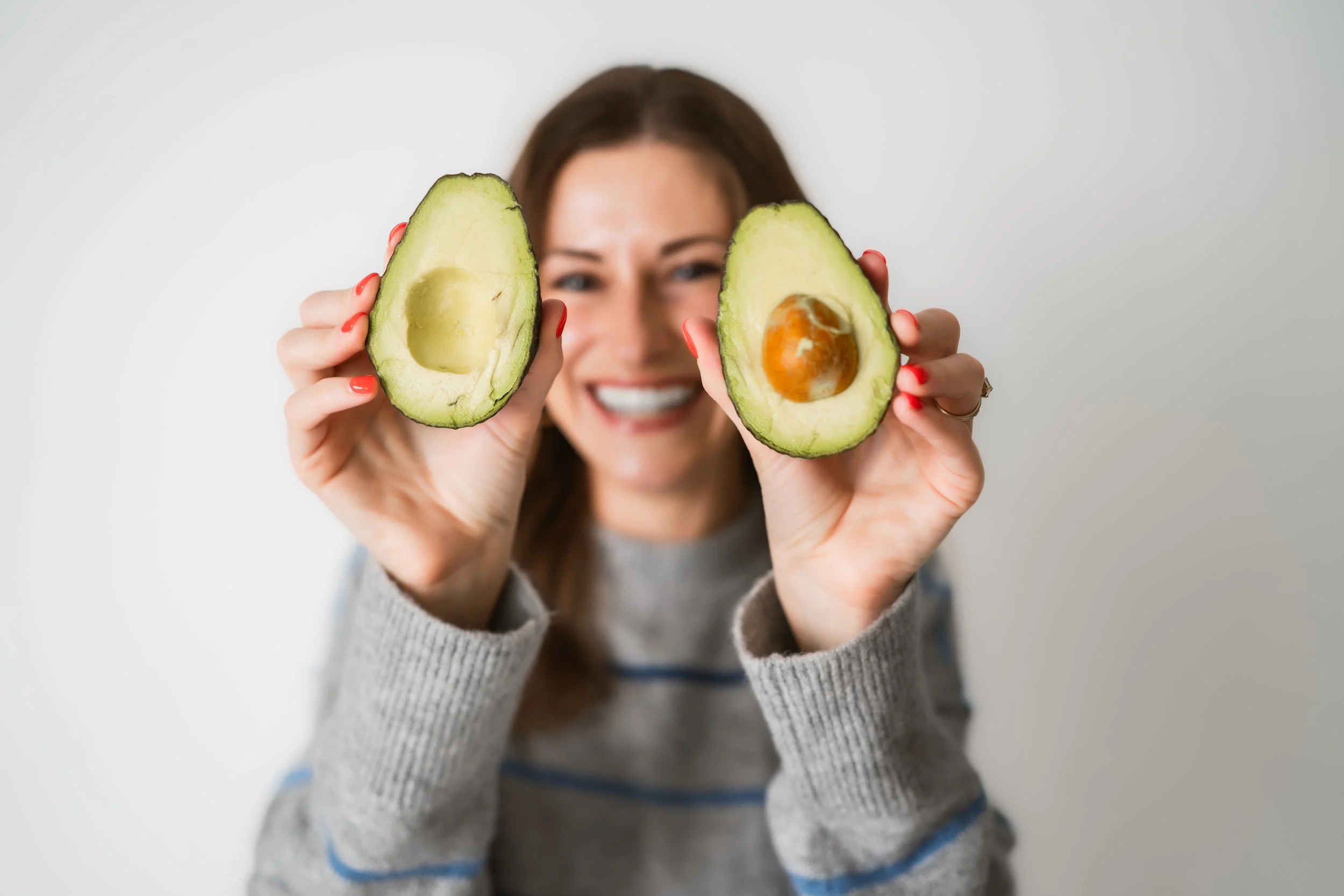 Sports dietitian holding avocado halves representing healthy fueling for athletic performance