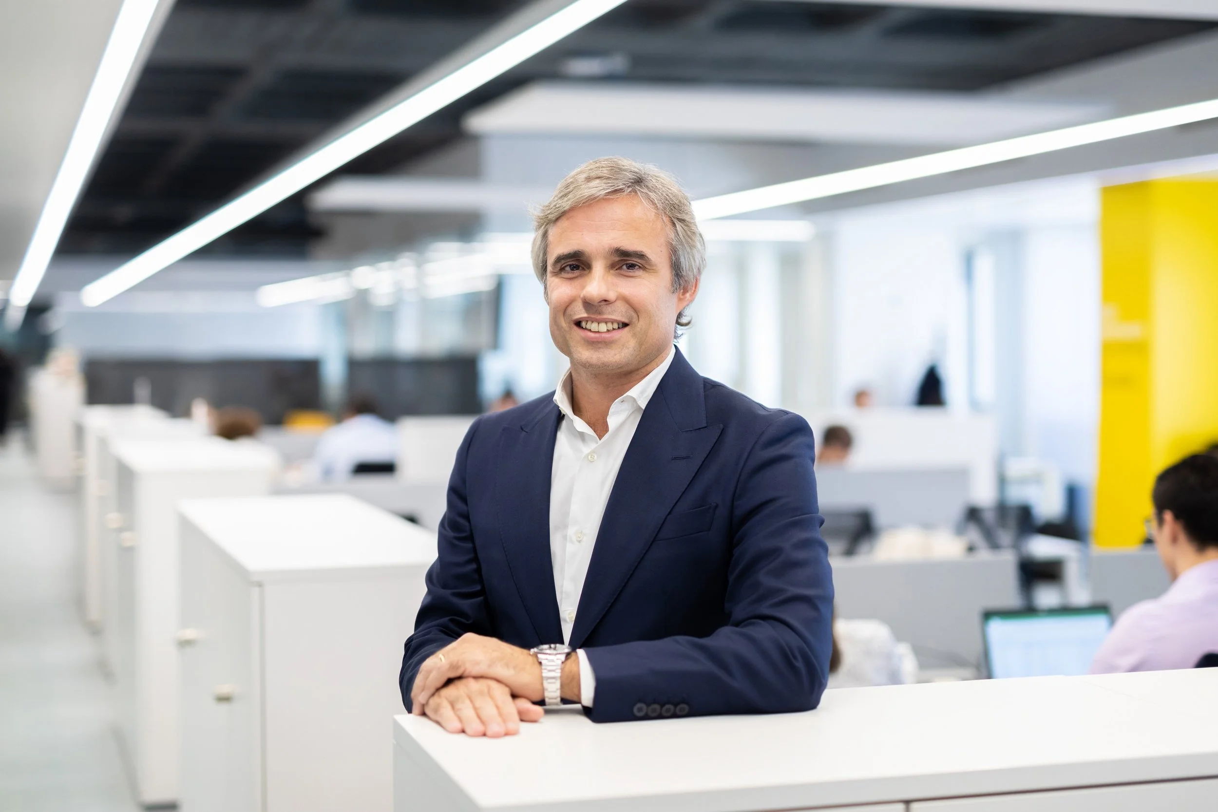 Smiling person in a suit with a blurred office background.