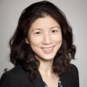 Man wearing a gray suit and glasses, smiling at the camera.