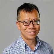 Smiling person with glasses wearing a checkered shirt