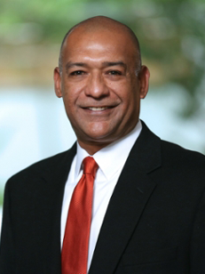 Man in a suit with a red tie standing outdoors
