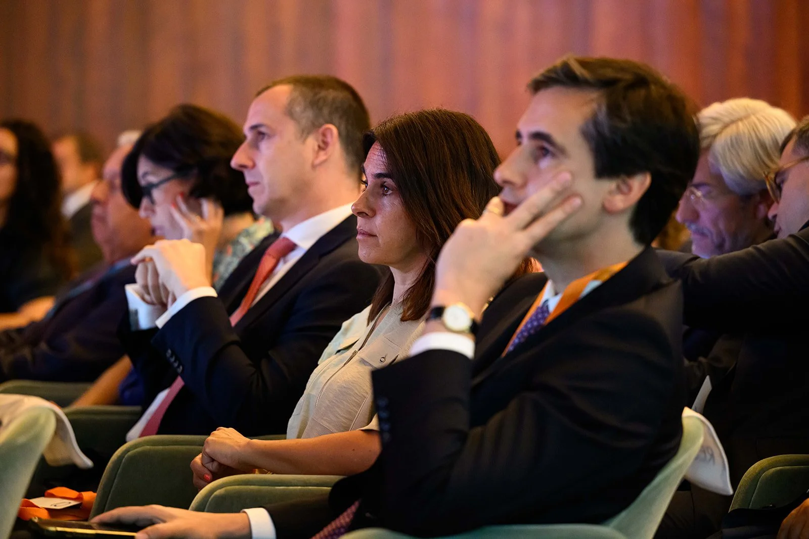 Business professionals attending a conference, sitting in rows and listening attentively.