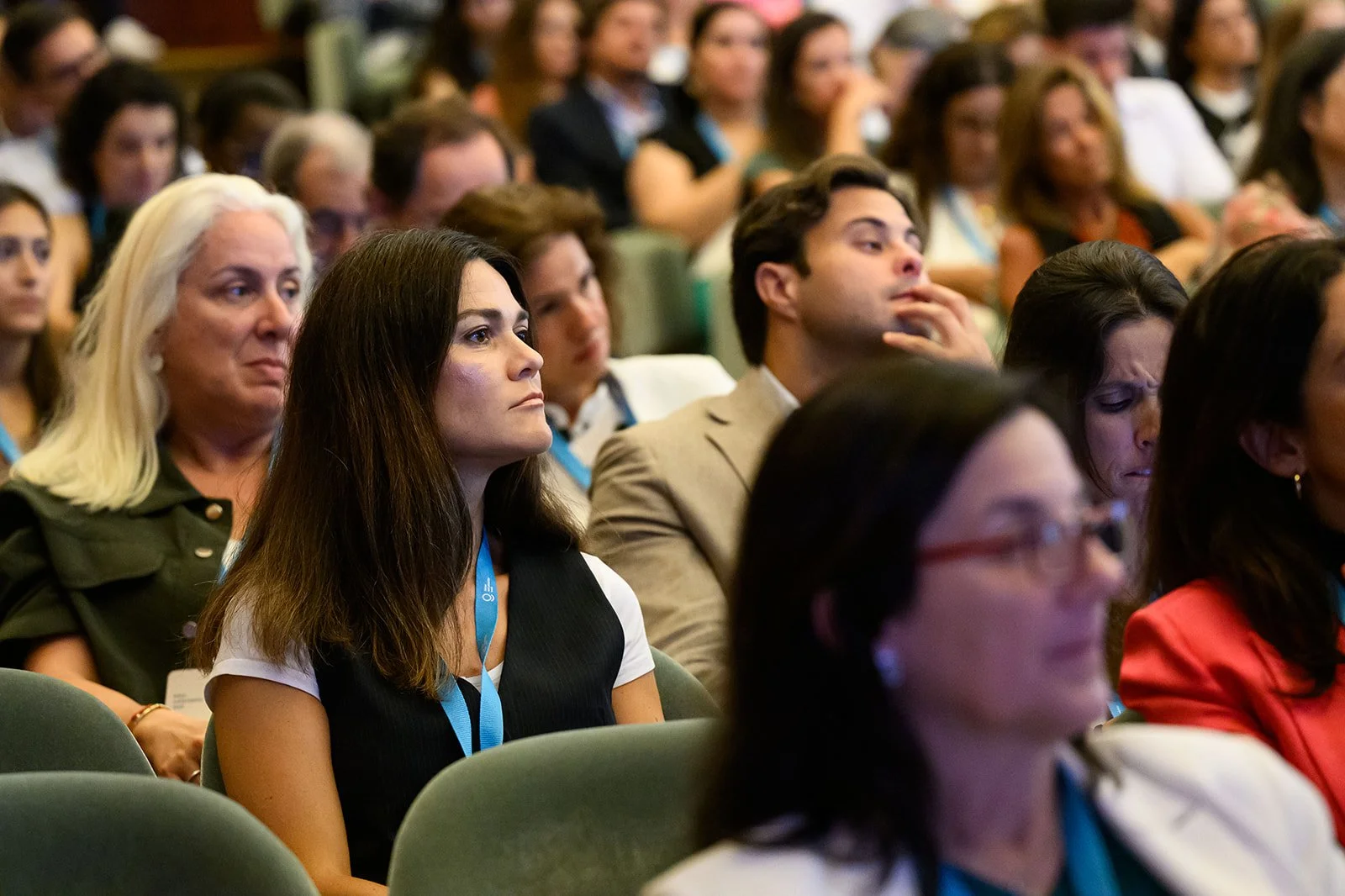A group of diverse people attending a conference or seminar, seated and listening attentively.