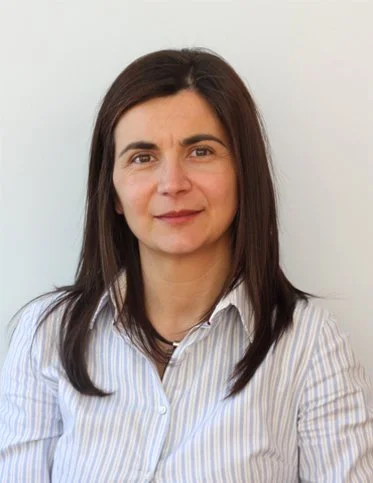 Woman with brown hair wearing a striped shirt against a plain background