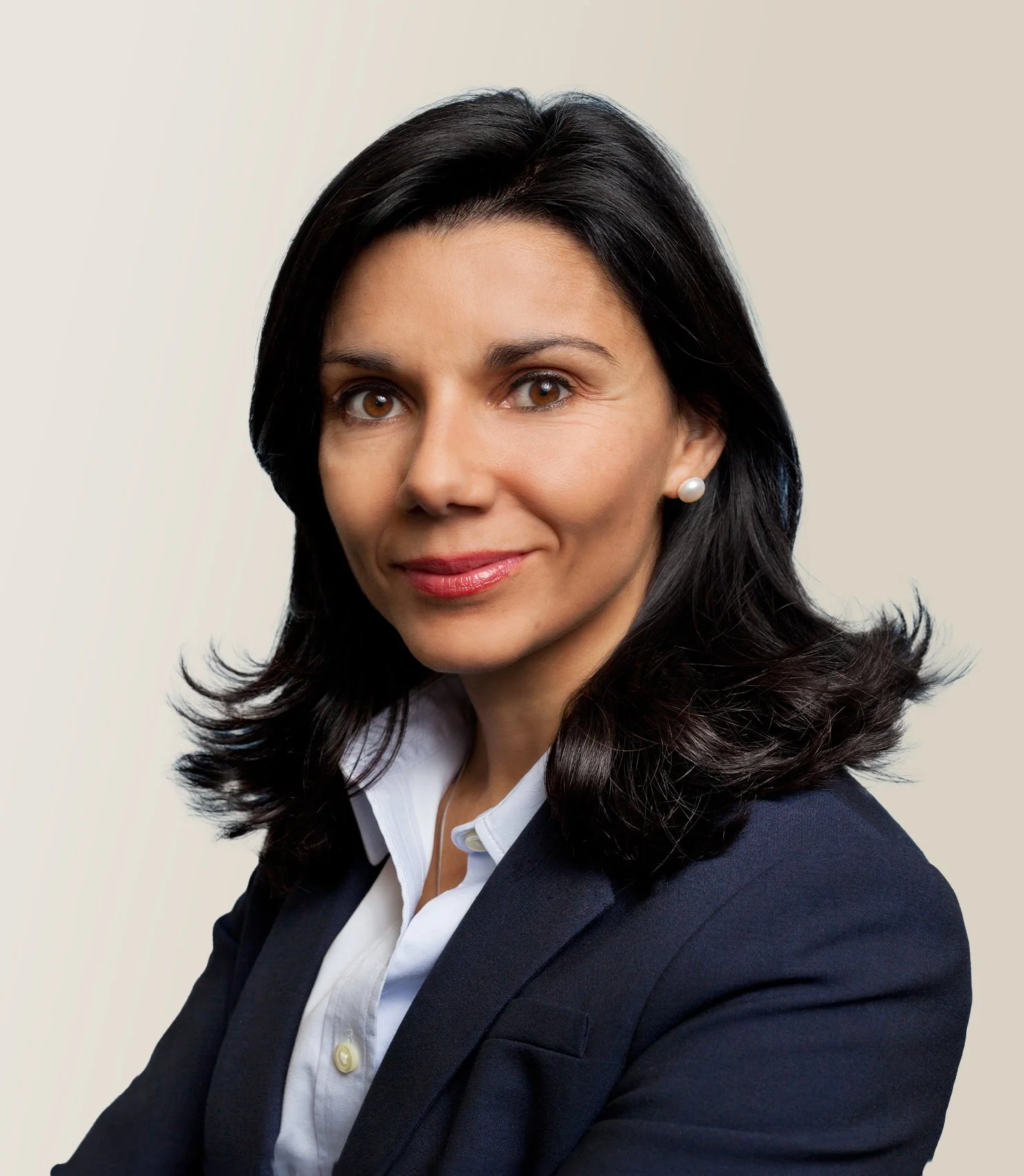 Portrait of a woman with dark hair wearing a suit with a white shirt, smiling.