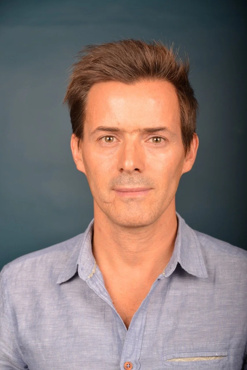 Man wearing a blue shirt against a blue background.