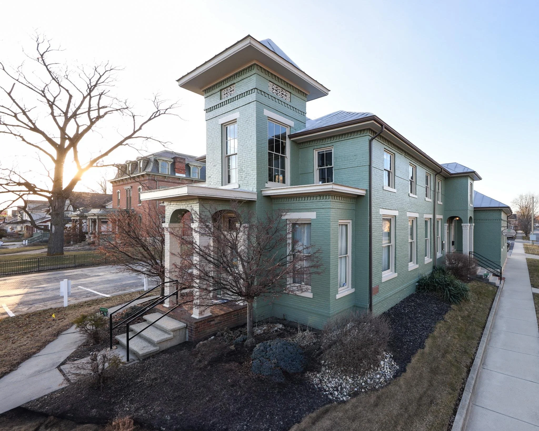 RCR Technology's business exterior in downtown Findlay, Ohio. A historic light green brick house with white accents and large windows.