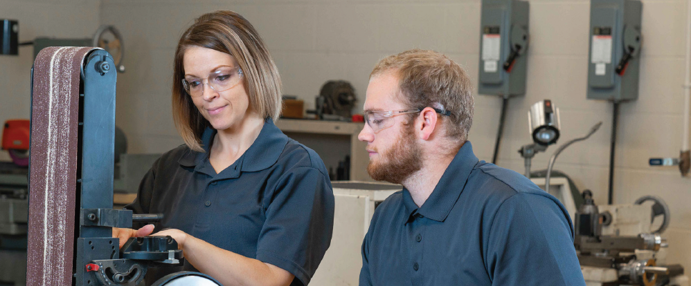Female and male apprentices using machinery.