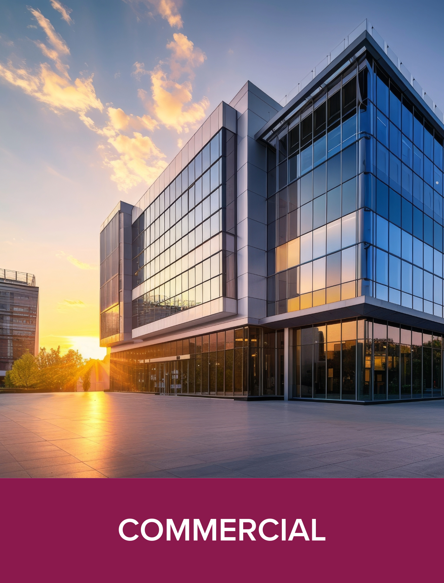 Modern glass commercial building at sunset with a spacious paved plaza in the foreground.