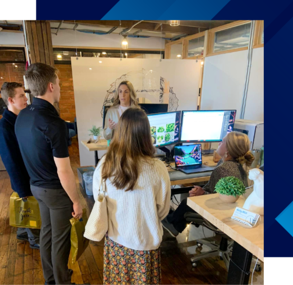 High school students participating in a career exploration visit while an employer explains workplace projects, technology, and career opportunities in an office setting.