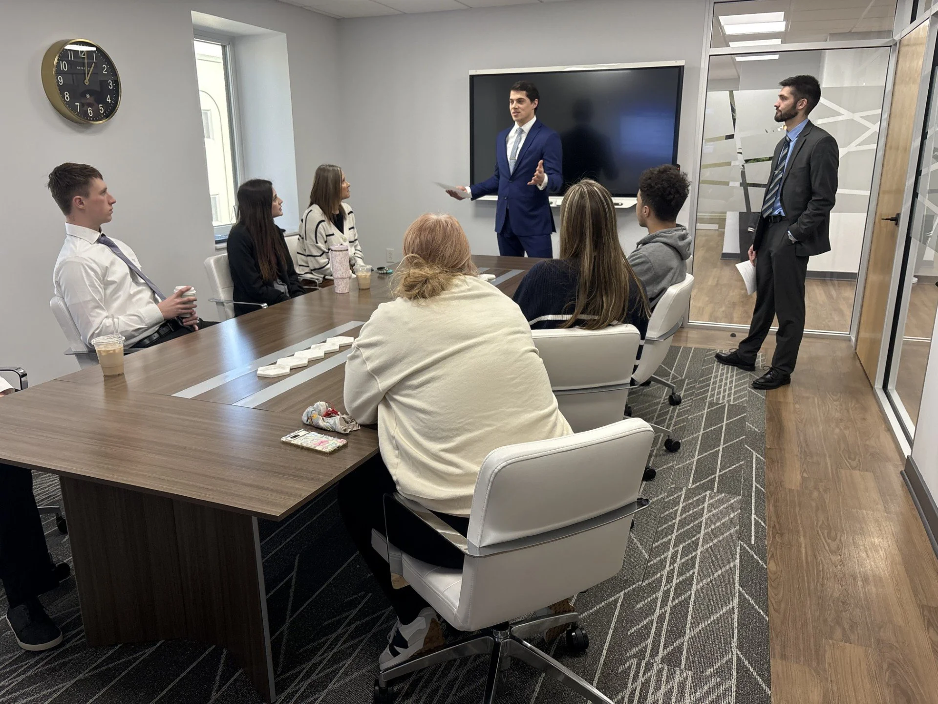 A group of people attending a presentation or meeting in a conference room with an office setting.