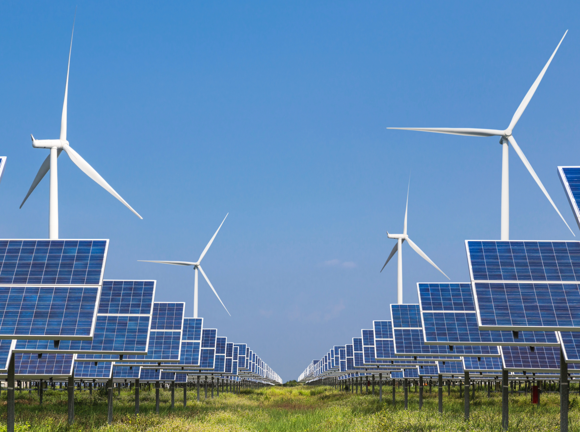A solar farm with rows of solar panels and wind turbines.