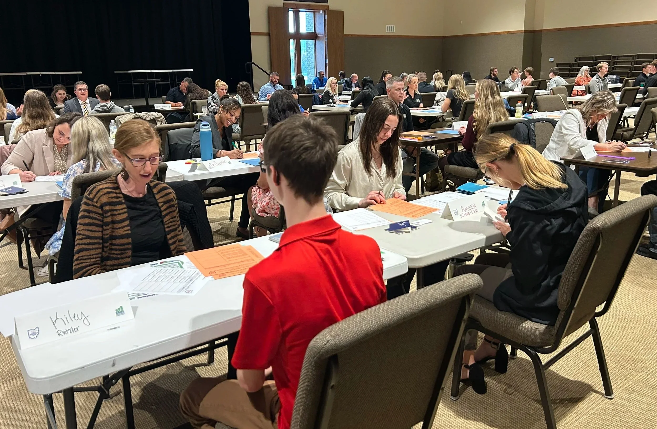 Room filled with high school juniors practicing their interviewing skills with business professionals.