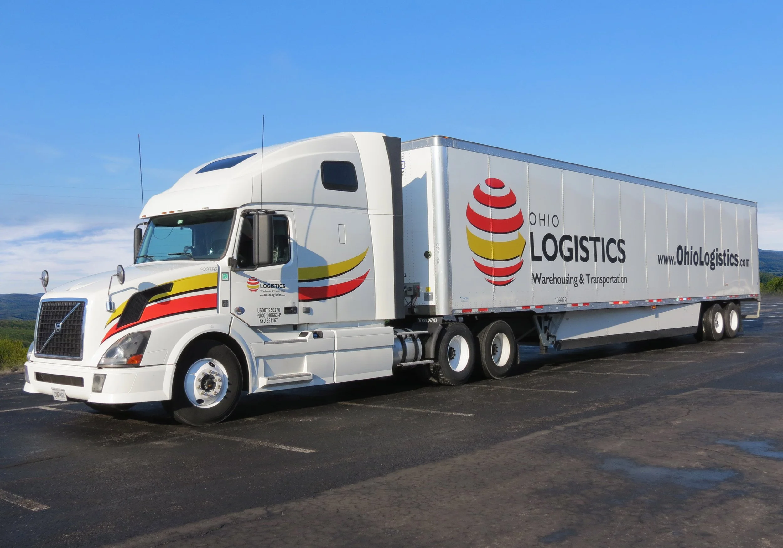 A white semi-truck with colorful logo and text on the side, labeled Ohio Logistics, parked outdoors.
