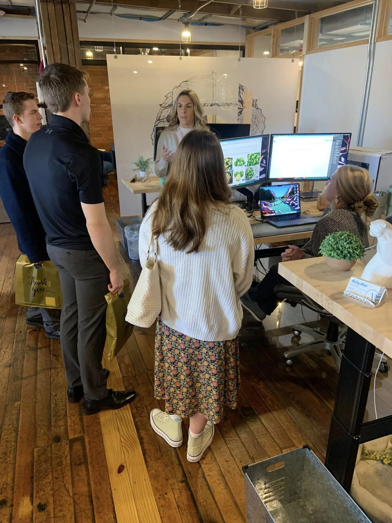 High school students participating in a career exploration visit while an employer explains workplace projects, technology, and career opportunities in an office setting.