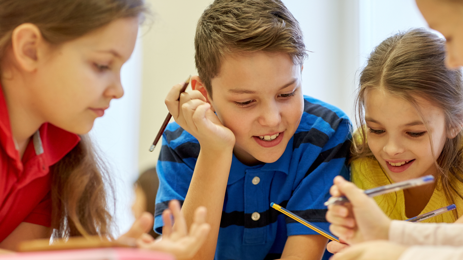 Elementary students interacting on assigment around a table.