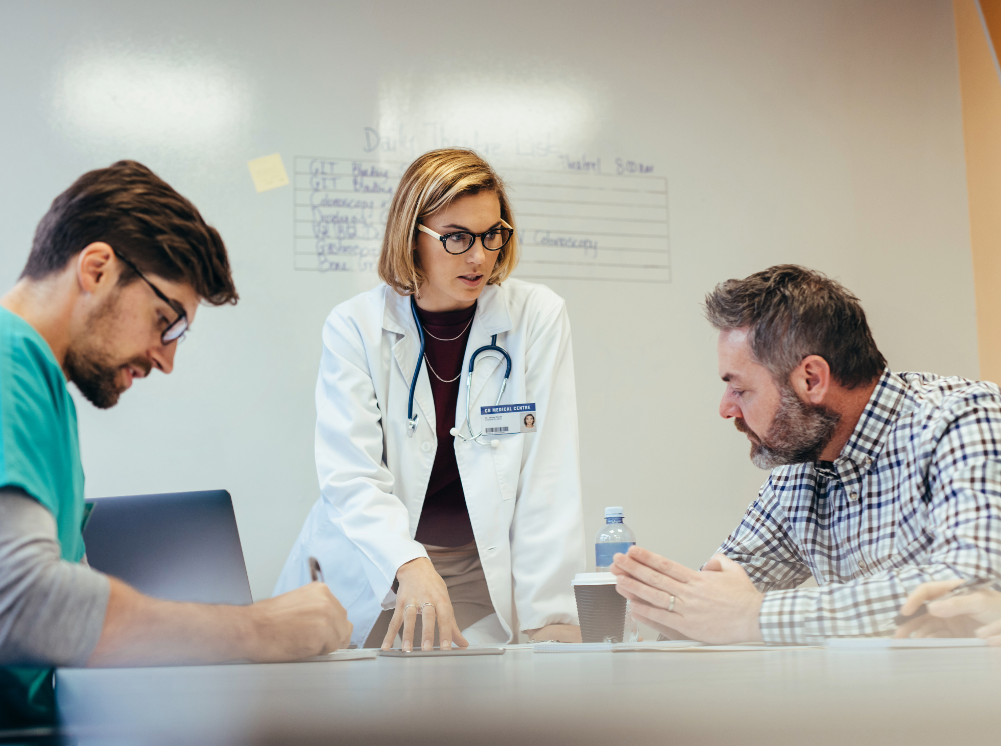 A female healthcare professional addresses two males in a clinical setting.
