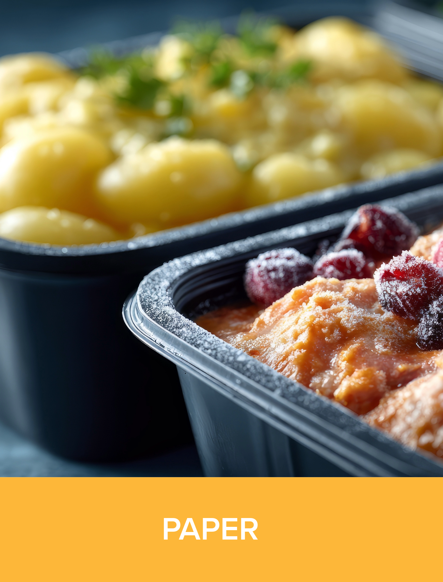 Close-up of food in black plastic containers, with one containing mashed potatoes and turkey topped with cranberries, and the other with yellow potatoes garnished with green herbs.
