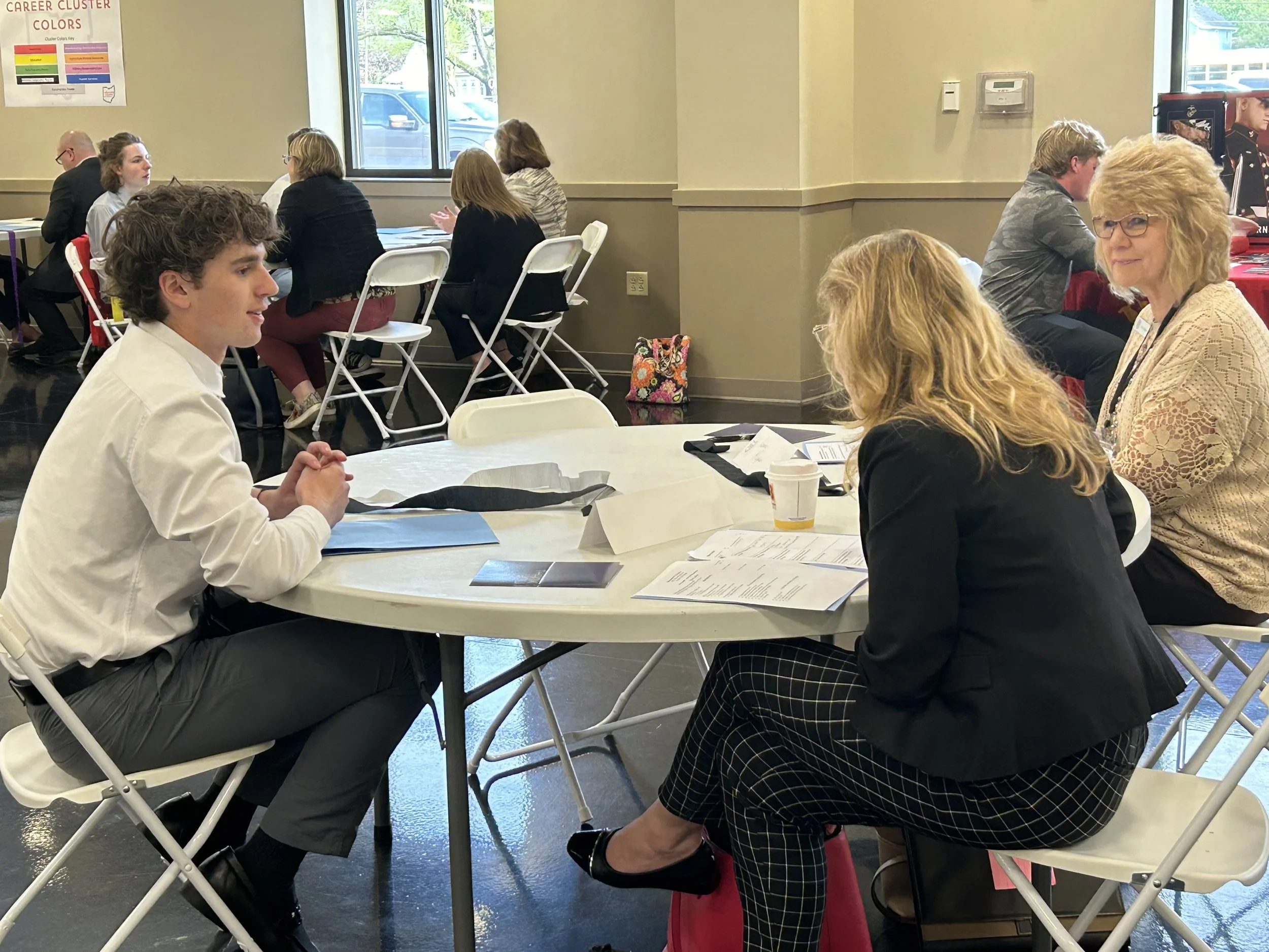 High school students practices interviewing skills with two business professionals during mock interview.