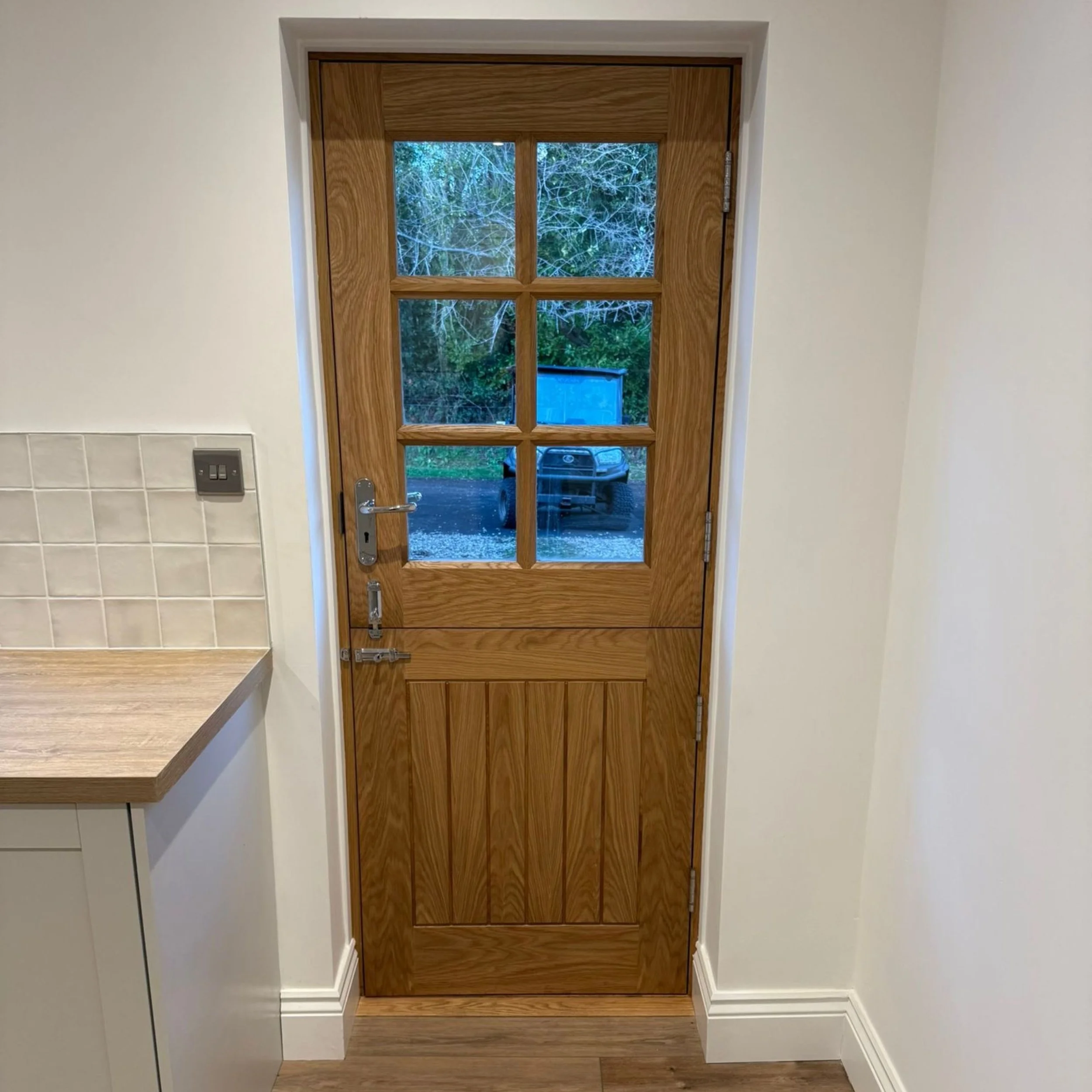 Interior view of a wooden door with glass panels, outside view shows a truck and trees.
