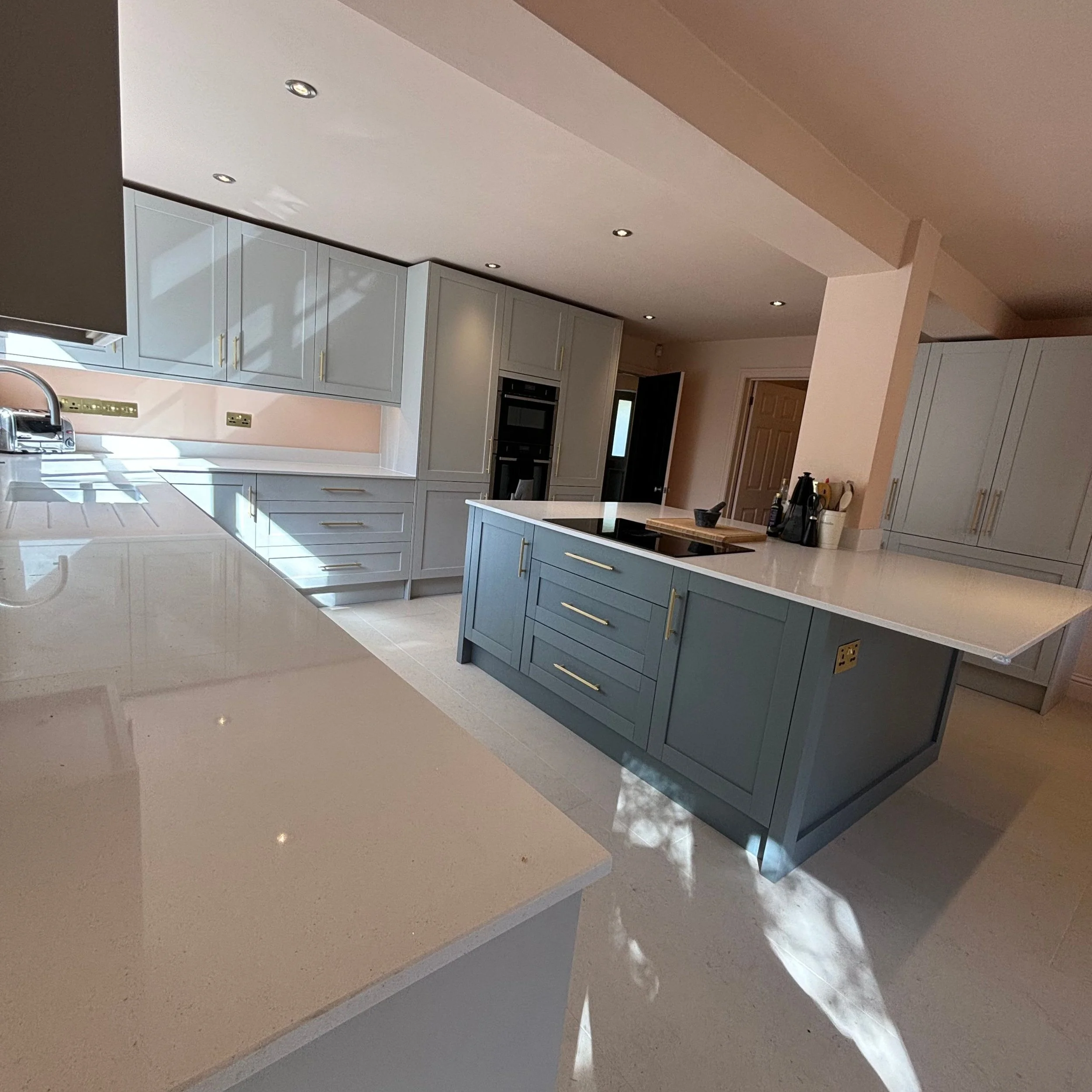 Modern kitchen with white and blue cabinets, cream countertops, and recessed ceiling lights