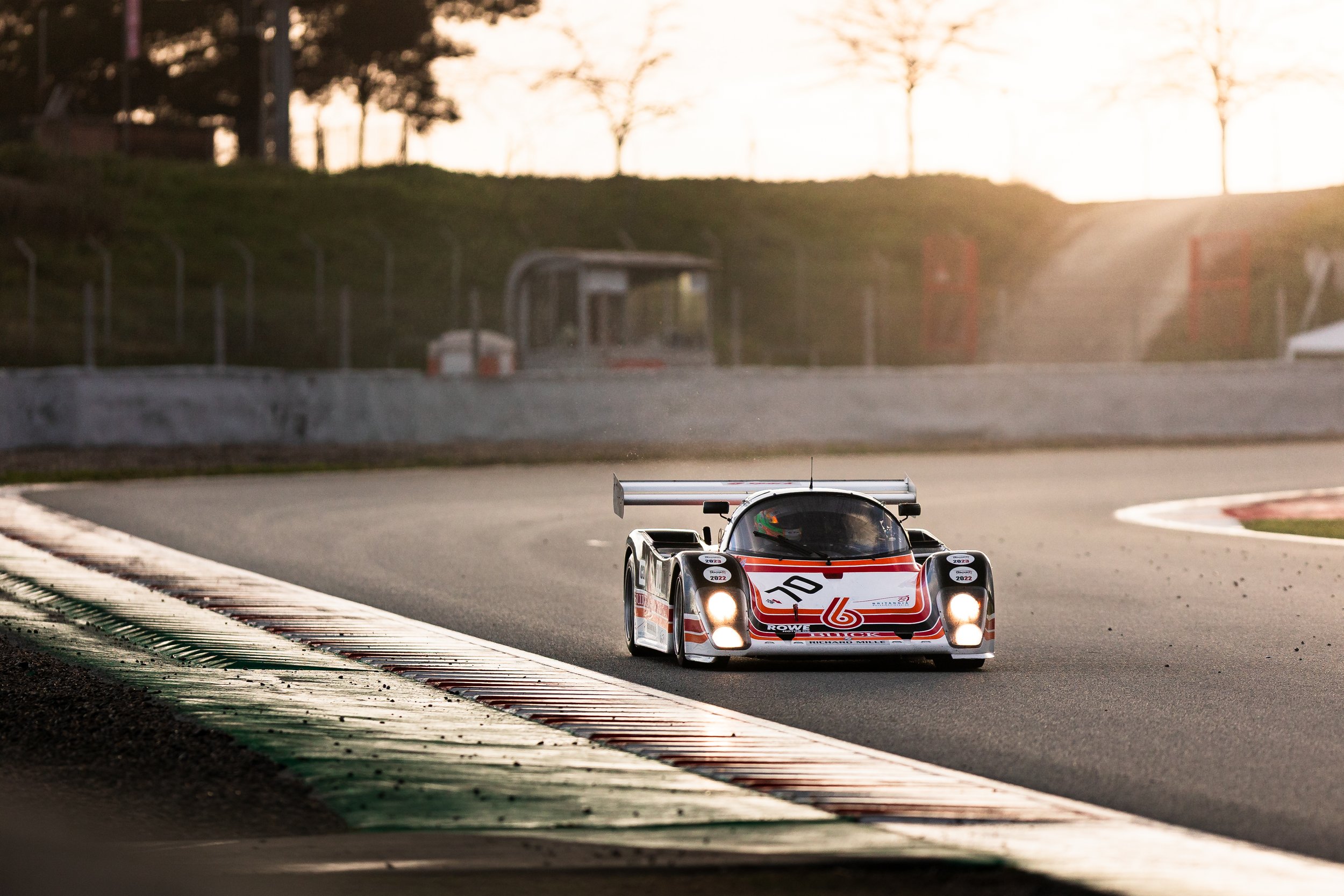 Race car driving on a track at sunset, approaching a corner. Peter Auto Barcelona Classic 2025. Legacy Outlaws Racing Team. Tiga GT286 Group C.