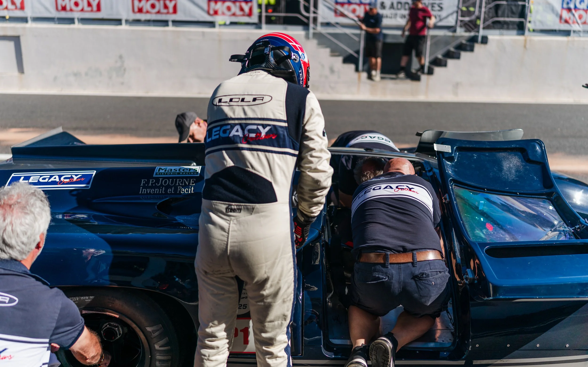 Race car team conducting maintenance on a vintage race car in the pit lane during a race. Legacy Outlaws Racing Team. Peter Auto Estoril Classic 2025. Chris Ward and Jan Magnussen. 