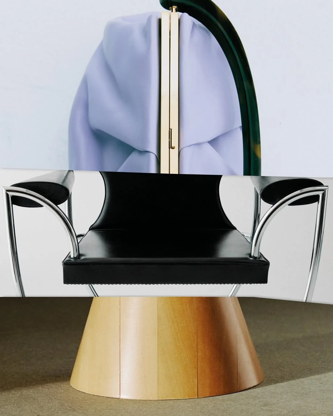 Une installation artistique composée de trois parties superposées : une pièce en forme de sac ou de vêtement en haut, une chaise noire avec des accoudoirs en métal au milieu, et une base en forme de cône en dessous.