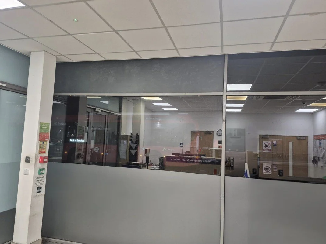 Empty ATM lobby area with glass windows and doors, signs, and notices on walls and counters.