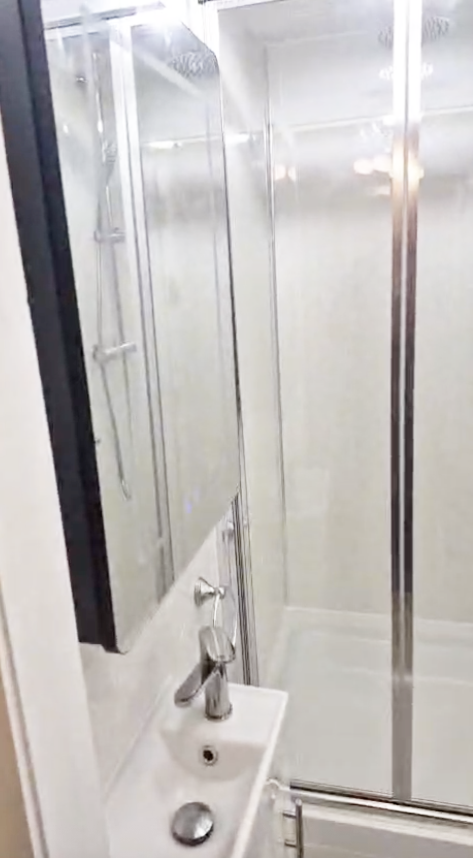 Small bathroom with a shower, a white sink with a chrome faucet, and a mirror cabinet above the sink.