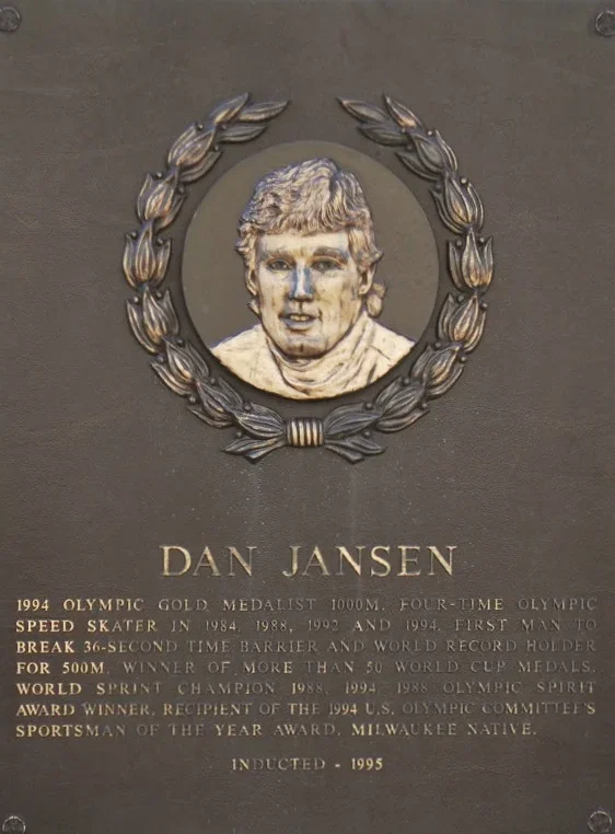 Plaque with a portrait of Dan Jansen, a gold medalist speed skater, surrounded by a laurel wreath, with biographical details and achievements listed.