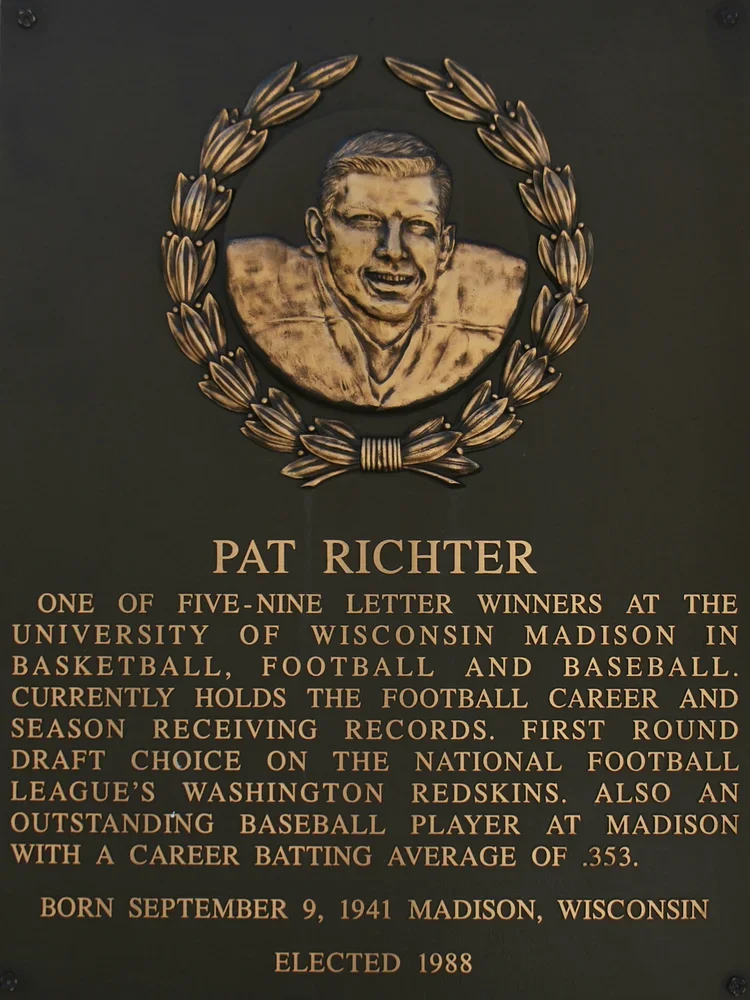 Plaque featuring a portrait of Pat Richter surrounded by a laurel wreath, with text detailing his athletic achievements and biographical information.